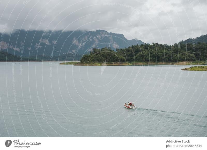 Boot schwimmt auf ruhigem Meer in der Nähe von Berg unter bewölktem Himmel in Thailand Schwimmer Berge u. Gebirge MEER Wasser wolkig Natur malerisch Kamm