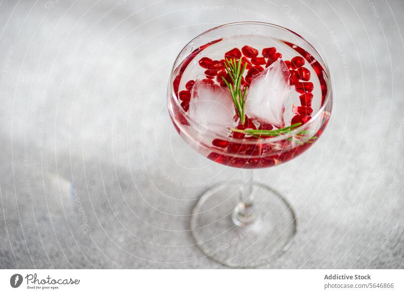 Granatapfel-Gin-Tonic im Betonhintergrund Cocktail Samen Rosmarin Glas Alkohol Getränk trinken Eis grau Hintergrund texturiert Mixologie Bar Aperitif