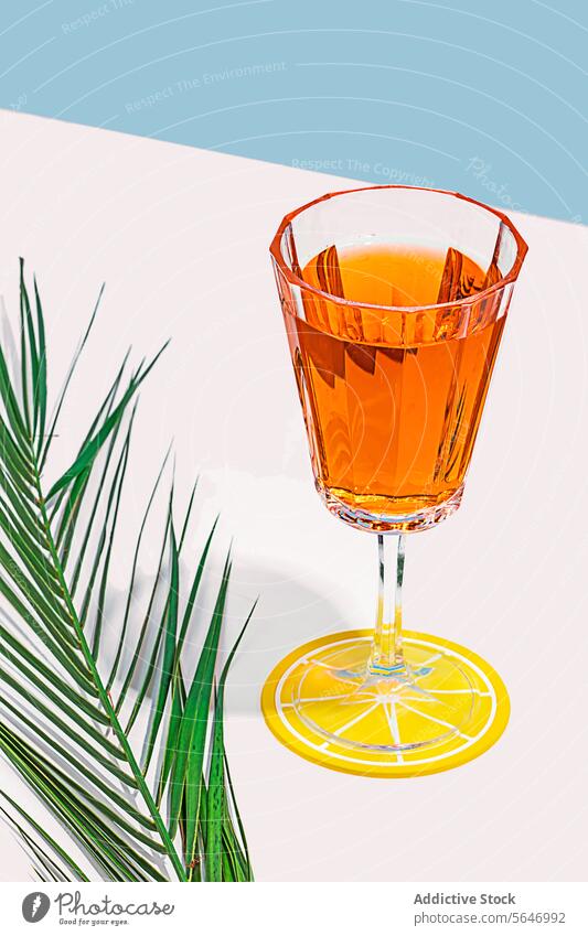 Elegantes Cocktailglas vor lebhafter Kulisse Glas Bernstein Kristalle Zitrusfrüchte Untersetzer Handfläche frond Pastell Hintergrund trinken stylisch pulsierend