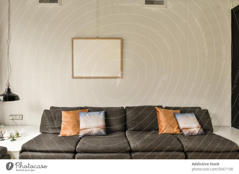 Wohnzimmer mit grauer Couch und Kissen groß Sofa Liege modern Zeitgenosse Schmuckanhänger Licht heimwärts Haus blanko Rahmen Wand weiß Textfreiraum erhängen