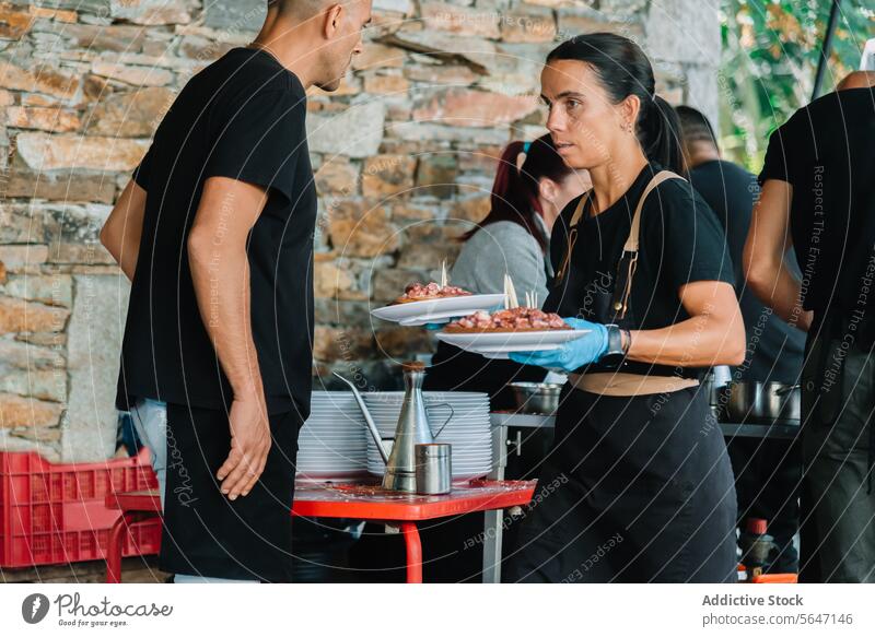 Kellnerin mit blauen Handschuhen trägt Teller mit gekochtem Oktopus Servieren galicisch Octopus kulinarisches Fest frisch Server Platten geschäftiges Treiben