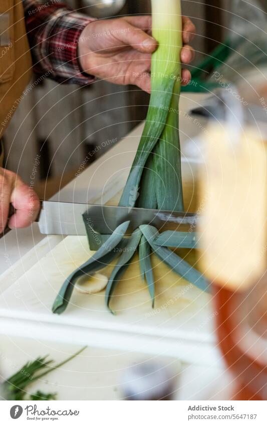 Anonyme Person Zubereitung von Lauch in der Küche Küchenchef Hände vorbereitend Lauchstangen Schneidebrett kulinarisch Rezept Essen zubereiten grün weiß neutral