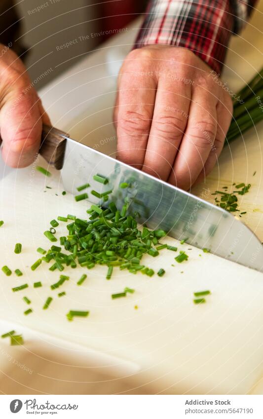 Nahaufnahme einer anonymen Person, die frischen Schnittlauch schneidet zerkleinernd Hände Schneidebrett grün Essen zubereiten Vorbereitung Küchenkräuter