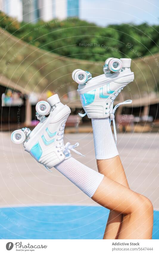 Crop weibliche Skaterin hebt Beine mit Roller-Sneaker Skates Park Person Bein angehoben Schlittschuh Sportpark aktiv Training üben Turnschuh Gesunder Lebensstil
