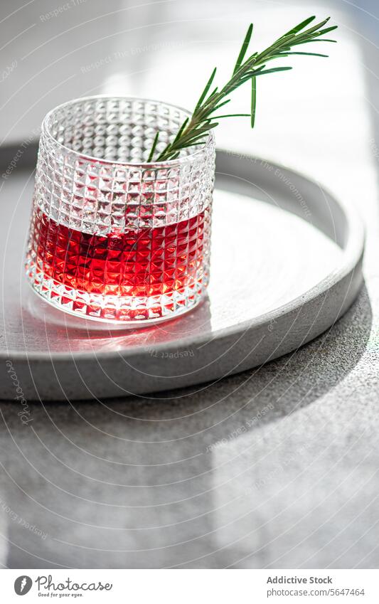 Eleganter Cocktail mit Kirsch- und Apfelsaft, gemischt mit Wodka, garniert mit einem frischen Rosmarinzweig, präsentiert auf einem runden Tablett Kirsche Saft