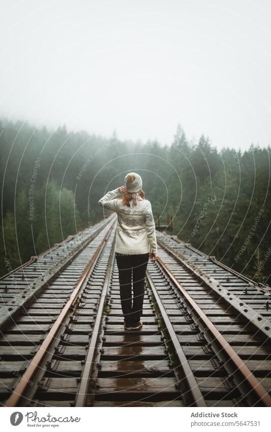 Rückansicht einer einsamen Frau auf einer nebligen Zugstrecke auf Vancouver Island Person Eisenbahn Nebel British Columbia Kanada Zuggleis Kontemplation