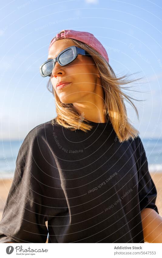 Hübsche Frau am Meer an einem sonnigen Tag stylisch Sonnenbrille Verschlussdeckel Strand blond schön Blick nach hinten Schulter Seeküste hübsch modisch