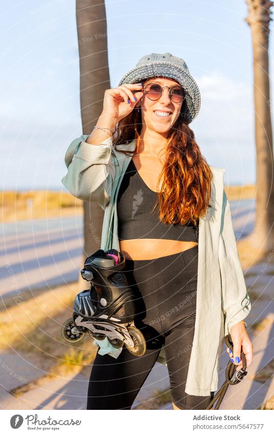 Modische attraktive Frau mit Schlittschuhen inline Sonnenbrille Hut modisch Glück brünett schön Rolle Lifestyle Rollschuhfahren Sonnenlicht