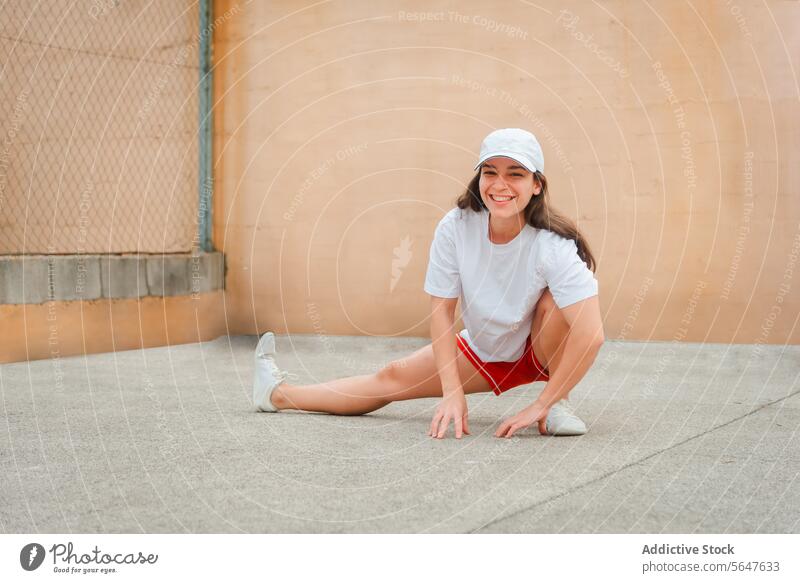 Aktive Frau in sportlicher Kleidung dehnt sich im Freien strecken aktiv Übung Fitness Gesundheit Lifestyle heiter jung Verschlussdeckel Sport