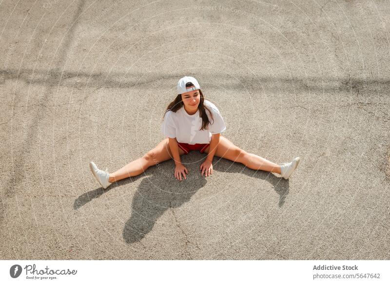 Junge Frau ruht sich nach dem Training auf Betonboden aus jung sportlich aussruhen Boden im Freien Verschlussdeckel Sportbekleidung Sitzen Freizeit aktiv
