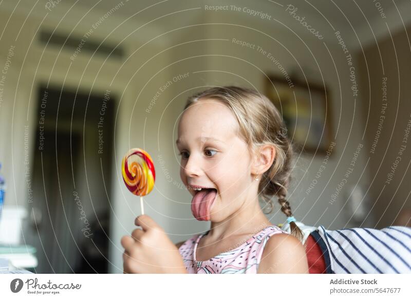 Junges Mädchen genießt bunten Lutscher zu Hause Lollipop Bonbon Freude Kind süß Leckerbissen Snack Dessert Fröhlichkeit Genuss spielerisch Zucker Geschmack