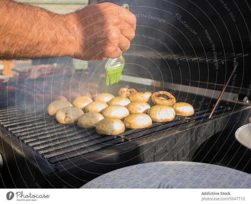 Unbekannter Mann, der Pilze auf einem Rost grillt Küchenchef Barbecue Grillrost Koch Erdöl Bürste Ablage männlich Erwachsener Hand stehen Prozess kulinarisch