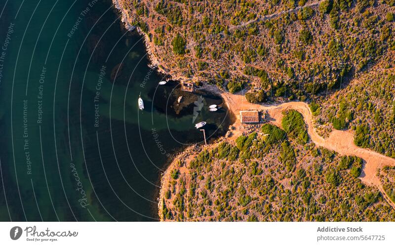 Luftaufnahme des Naturhafens Sanitja auf Menorca mit kurvenreicher Straße entlang der zerklüfteten Küste Portwein Cavalleria Balearen Küstenlinie Serpentinen