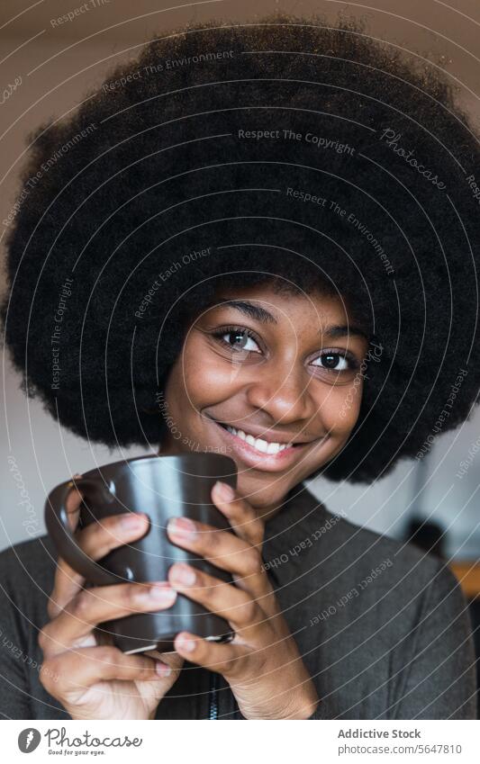 Positive schwarze Frau mit Heißgetränk Tasse Getränk Kaffee Afro-Look feminin Frisur verträumt Lächeln Vorschein Glück charmant brünett attraktiv heiter Inhalt