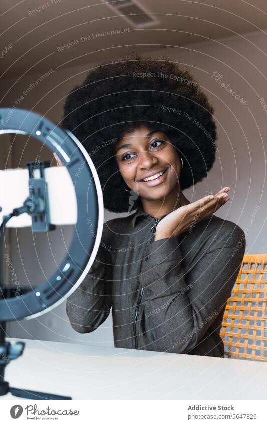 Fröhliche schwarze Frau nimmt Vlog auf vlog Blogger Smartphone Ringlampe Aufzeichnen Video soziale Netzwerke online Afro-Look Lächeln Freizeit Frisur feminin