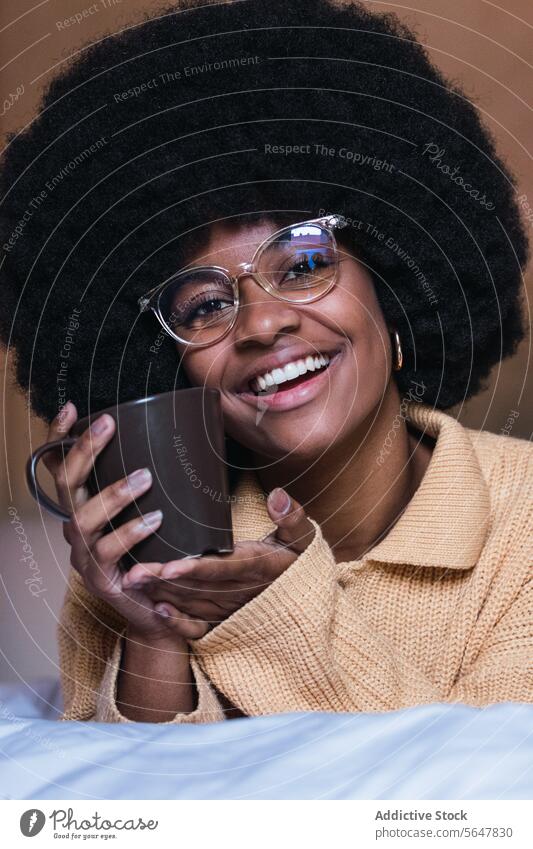 Lächelnde schwarze Frau mit Kaffee im Bett ruhen sich[Akk] entspannen Wochenende Freizeit heimwärts Afroamerikaner Afro-Look Komfort Schlafzimmer Glück Brille