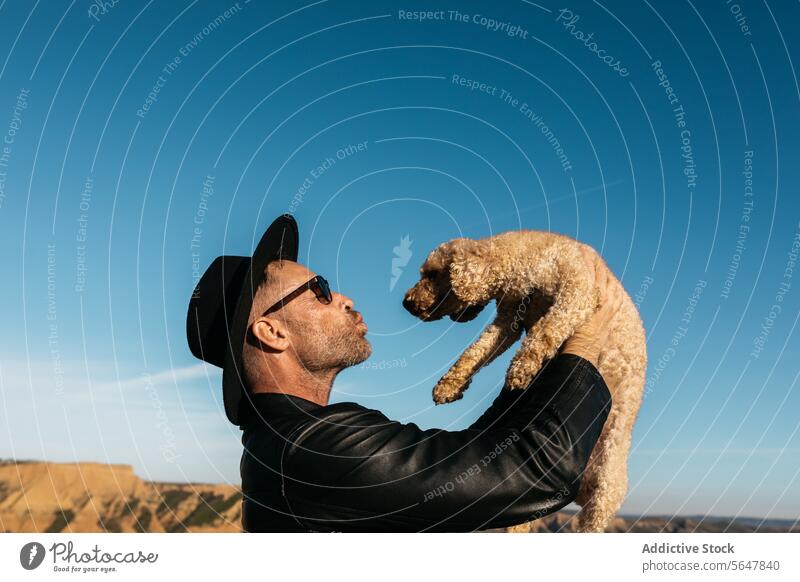 Freudiger Moment: Mann hebt Hund gegen blauen Himmel Blauer Himmel Kuss Freude Heben binden Haustier Begleiter Fröhlichkeit im Freien Freizeit Lifestyle
