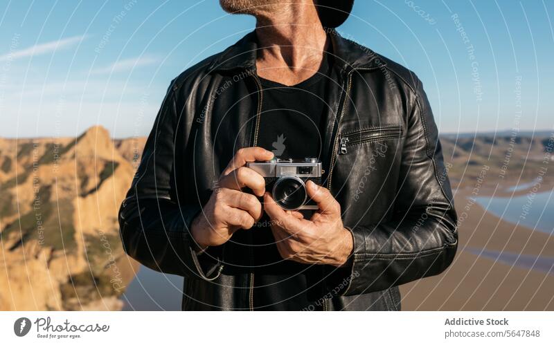 Stilvoller anonymer Mann erkundet die Natur mit einer alten Kamera Fotokamera altehrwürdig Fotograf wüst Entdecker abgeschnitten Abenteurer Landschaft stylisch