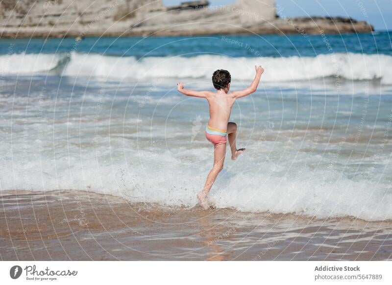 Fröhliches Kind spielt in den Wellen des Ozeans Strand Meer winken spielen rennen sonnig freudig Spaß Wasser MEER Sommer Urlaub Feiertag Sand Küstenlinie