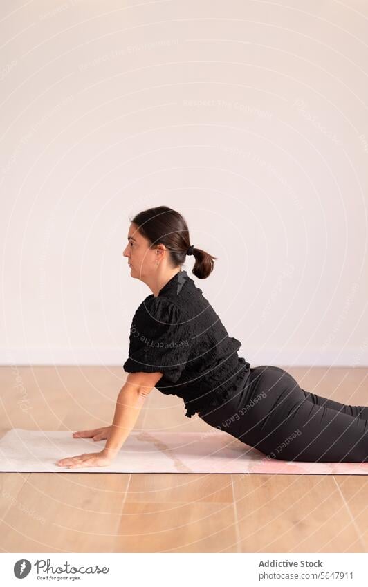 Frau beim Üben einer Yogapose auf einer Matte in einem Yogazentrum üben Training Unterlage Dame Sportbekleidung Übung Fitness beweglich Dehnung Aktivität Barfuß