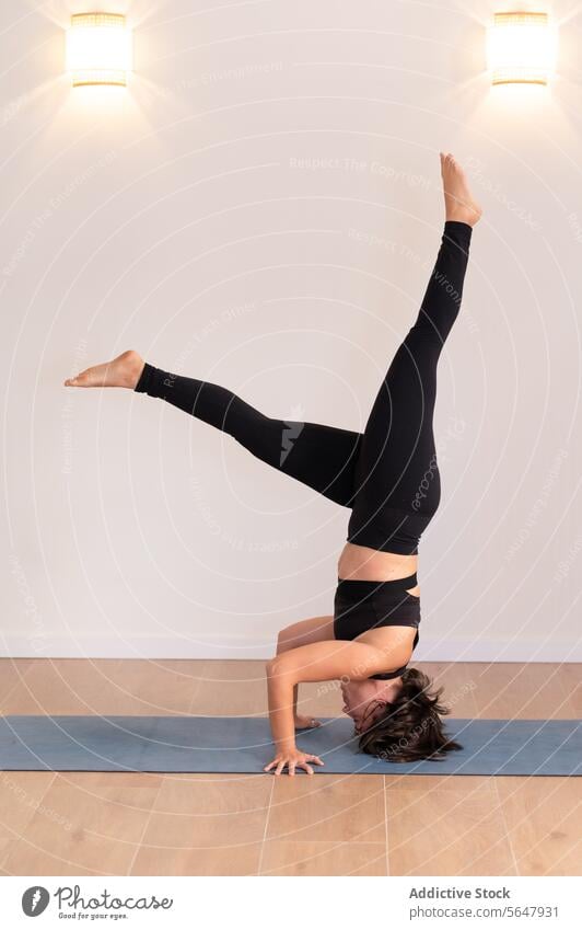 Flexible Frau im Kopfstand im Yogastudio ausführen Pose Sportbekleidung Dame beweglich üben Training Unterlage Übung leuchten Wellness Gesunder Lebensstil Raum