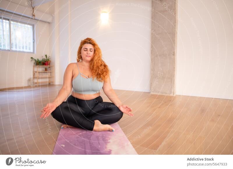 Konzentrierte kurvige Frau in Yoga-Asana-Pose im Yoga-Studio Konzentration üben Dame kurvenreich Sportbekleidung beweglich Barfuß Fitness Wellness Stressabbau