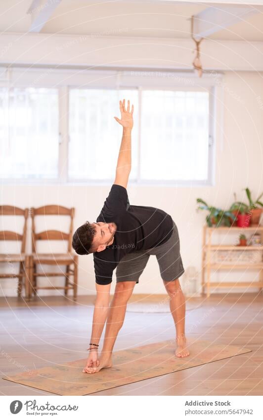 Flexibler Mann übt Dreieckspose beim Training üben ausführen Triangel-Pose Yoga Sportkleidung Sitzung Typ beweglich männlich Gleichgewicht Dehnung Asana