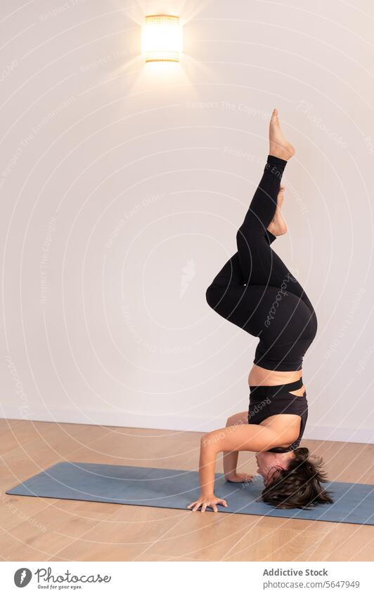 Flexible Frau in Handstand-Yoga-Pose im Fitnessstudio üben Kopfstand Sportbekleidung Training ausführen Sitzung beweglich Morgen Gleichgewicht Asana