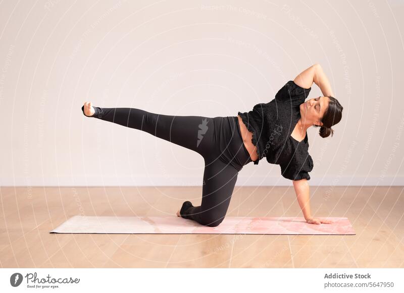 Konzentrierte Frau, die während einer Yogastunde auf der Matte trainiert Training Dehnung Sitzung Sportkleidung konzentriert Dame sportlich Übung Wellness üben