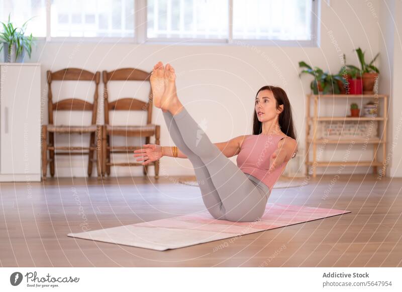 Konzentriertes Dehnen der Frau auf der Matte während der Yogapraxis sitzen Dehnung üben Sportbekleidung Training beweglich fokussiert Unterlage Dame Wellness