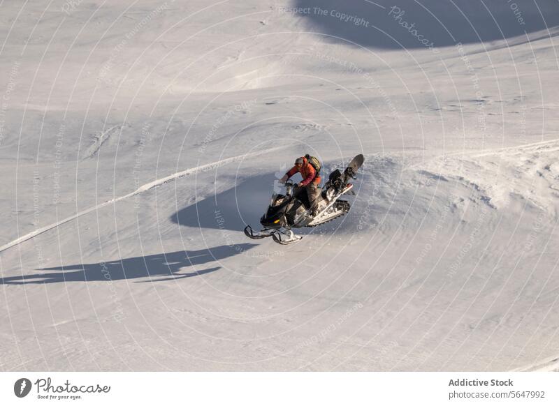 Anonyme Person fährt Schneemobil auf schneebedecktem Berg Schneefahrzeug Abenteuer warme Kleidung Mitfahrgelegenheit Schutzbrille Berge u. Gebirge Berghang