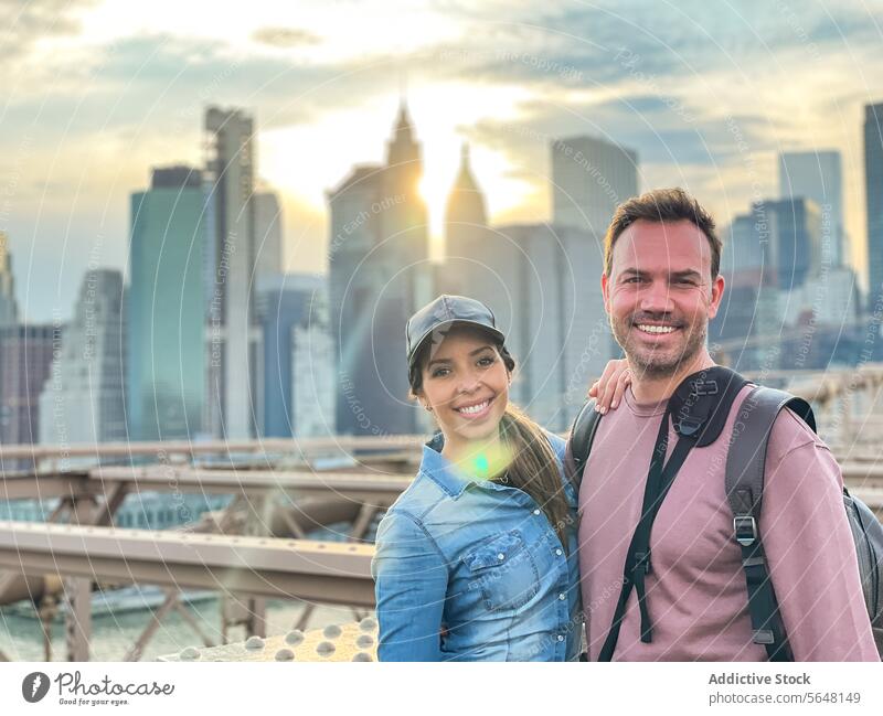 Mann und Frau auf der Brooklyn Bridge vor der Kulisse von Manhattan Skyline Sonnenuntergang New York State Rucksack Verschlussdeckel Lächeln Paar Stadtbild
