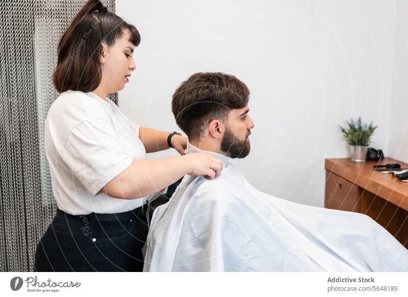 Seitenansicht einer fokussierten Friseurin, die sich darauf vorbereitet, die Haare eines männlichen Kunden im Salon zu schneiden Mann Behaarung Pflege Dienst