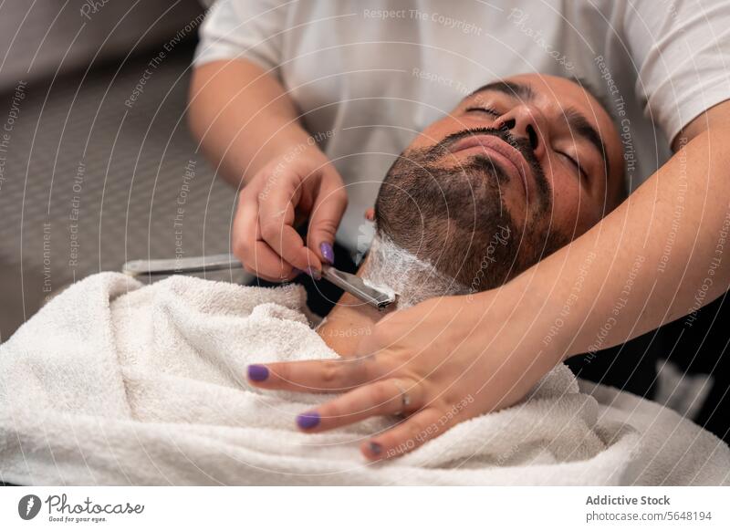 Barbierin rasiert den Bart eines männlichen Kunden mit einem Rasiermesser Friseur Rasieren Gerades Rasiermesser Vollbart Mann Salon Pflege Dienst Hand Klient