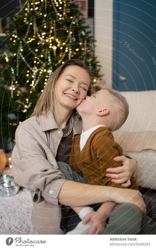Mutter und Sohn teilen einen freudigen Moment am Weihnachtsbaum Kuss Lächeln festlich Feiertag binden Familie Wärme Freude Zuneigung Zusammengehörigkeitsgefühl