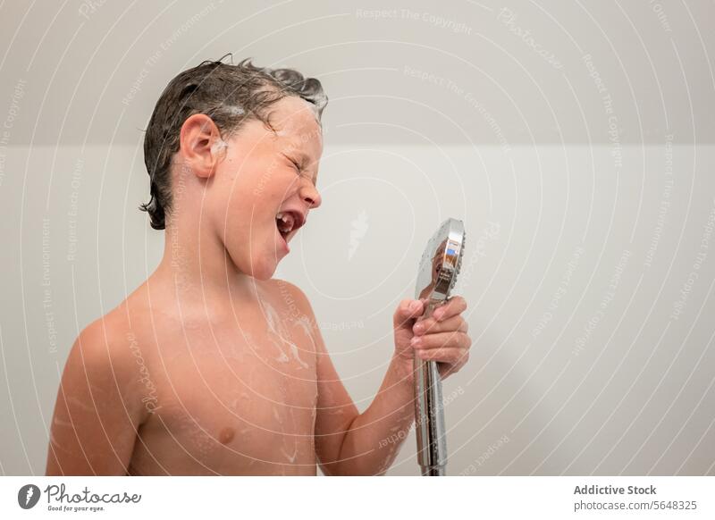 Junge hält Handbrause beim Baden im Badezimmer Dusche Porträt singen so tun, als ob träumen Kind Haarwaschmittel niedlich schäumen Hygiene Kindheit Spaß haben