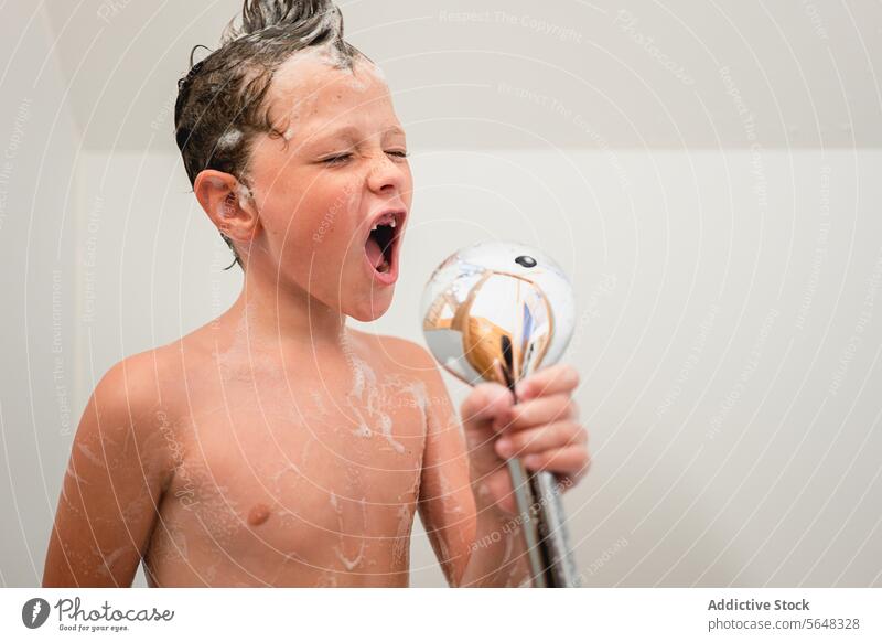 Junge hält Handbrause beim Baden im Badezimmer Dusche Porträt singen so tun, als ob träumen Kind Haarwaschmittel niedlich schäumen Hygiene Kindheit Spaß haben