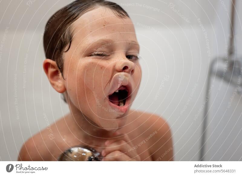 Kleiner Junge mit nassen Haaren macht Gesichter an Glaswand im Badezimmer Kind Dusche spielerisch Hygiene lustig wenig niedlich bezaubernd Spaß haben Kindheit