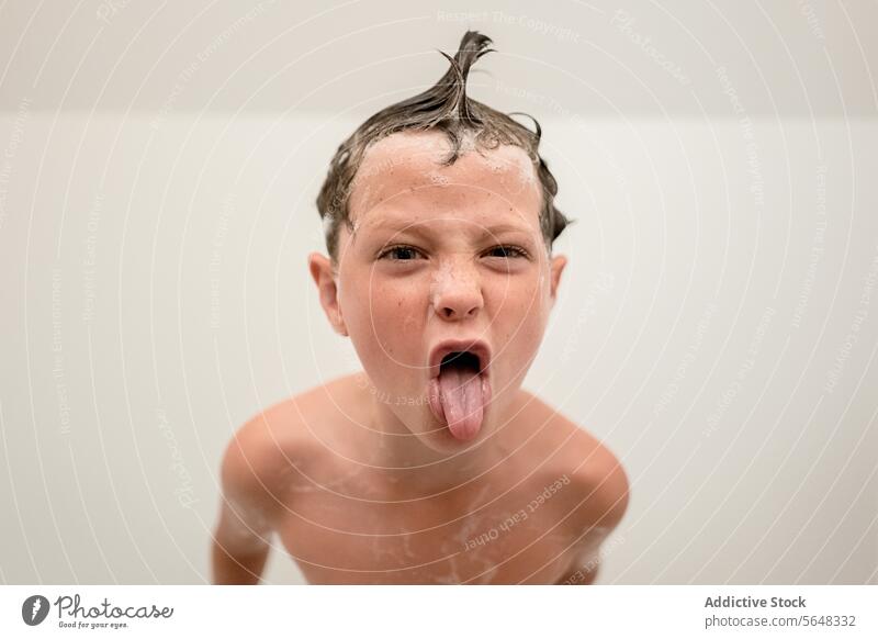 Lustiger kleiner Junge zeigt seine Zunge im Badezimmer heraus schäumen Mund geöffnet Dusche Hygiene Zunge zeigen Haarwaschmittel ausspannen Waschen Kindheit