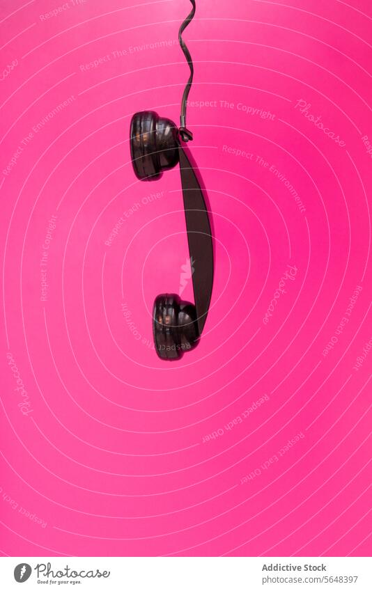 Hängender Empfänger auf rosa Hintergrund Telefonhörer erhängen schwarz getrennt Mitteilung Unterbrechung einsiedlerisch Schnur lebhaft Symbol altehrwürdig retro