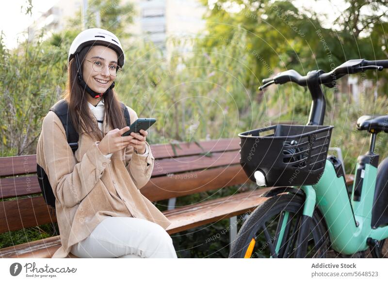 Lächelnde junge Frau mit E-Scooter im Freien E-Roller Schutzhelm Erwachsener elektrisch Tretroller Großstadt Weg sonnenbeschienen heiter Stehen Sicherheit
