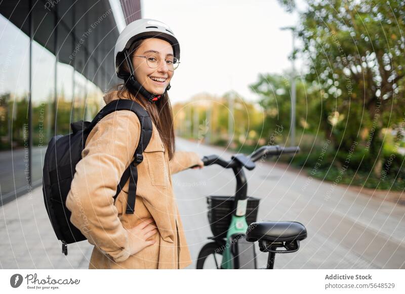 Lächelnde junge Frau mit E-Scooter im Freien E-Roller Schutzhelm Erwachsener elektrisch Tretroller Großstadt Weg sonnenbeschienen heiter Stehen Sicherheit