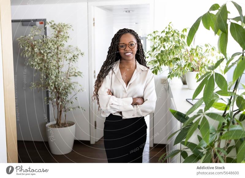 Porträt einer glücklichen schwarzen Geschäftsfrau mit verschränkten Armen im Büro Glück selbstbewusst Erfolg formal die Arme verschränkt Lächeln Frau heiter
