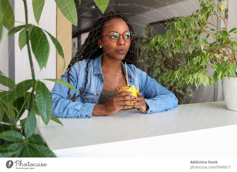 Geschäftsfrau bläst Kerze auf Cupcake in kreativem Büro Schlag nachdenklich Afro-Look jung Geburtstag feiern Lebensmittel Wegsehen professionell süß Business