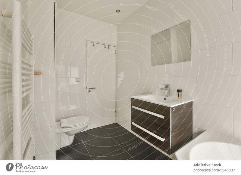 Innenraum eines weißen Badezimmers mit Toilette und Waschbecken Spiegel Schalen & Schüsseln Tür zugeklappt Fliesen u. Kacheln Wand montiert modern