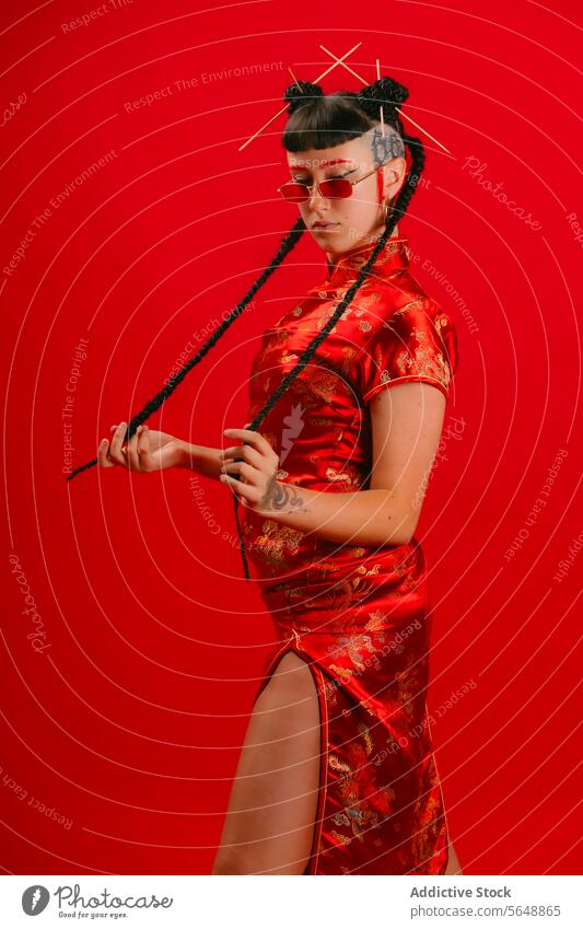 Stilvolle Frau in rotem traditionellen asiatischen Kleid vor rotem Hintergrund asiatisches Kleid Cheongsam Pose Zeitgenosse elegant Kultur Outfit Kleidung