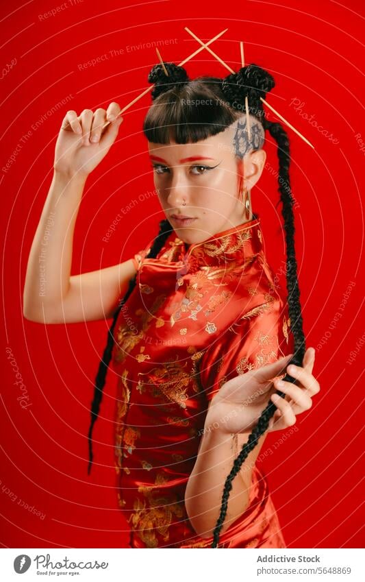 Stilvolle Frau in traditioneller asiatischer Tracht auf rotem Hintergrund Kleid Frisur Essstäbchen Pose selbstbewusst pulsierend modern einzigartig Kleidung