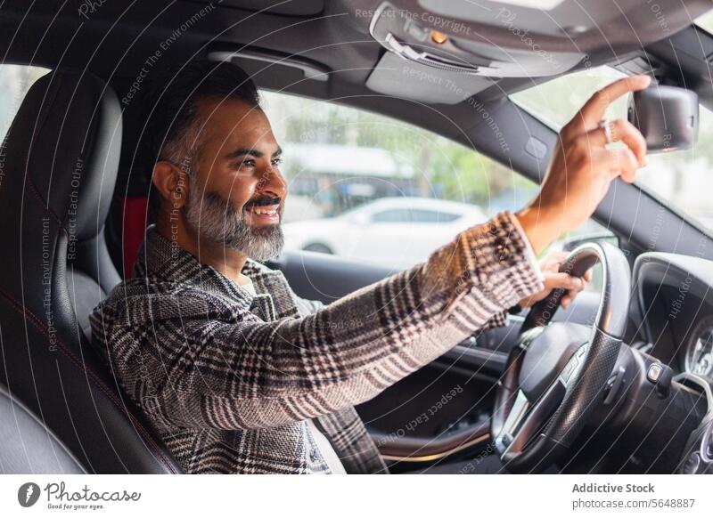 Lächelnder ethnischer männlicher Unternehmer, der im Auto sitzt und in den Rückspiegel schaut Mann Fahrer Geschäftsmann Lenkrad Automobil Laufwerk PKW Autoreise