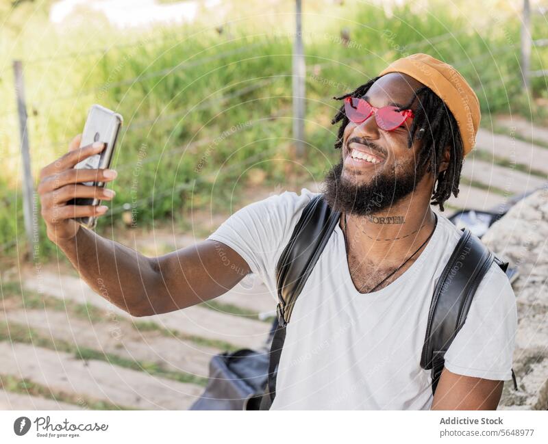 Fröhlicher männlicher Hipster macht Selfie im Park Mann benutzend Smartphone soziale Netzwerke Sommer Gedächtnis Moment Lächeln cool heiter jung schwarz