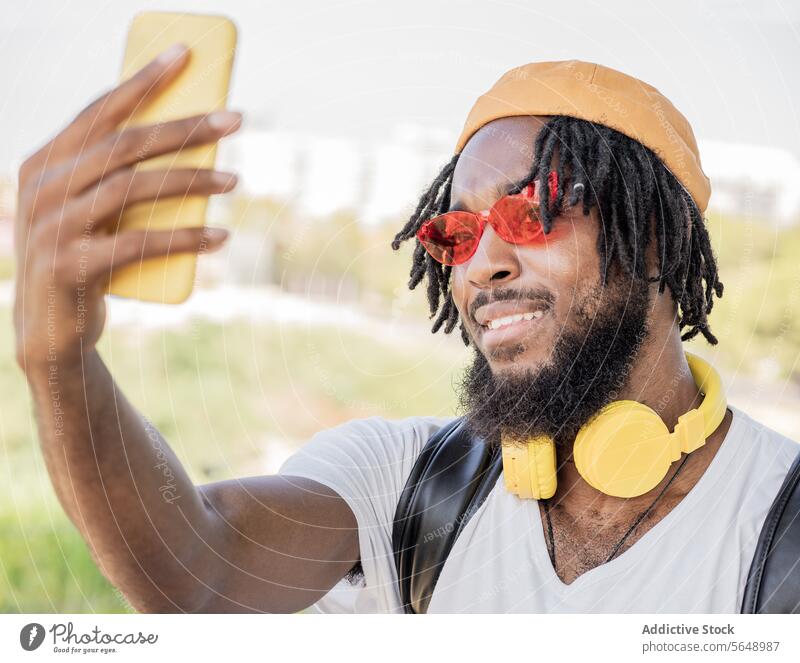 Fröhlicher männlicher Hipster macht Selfie im Park Mann benutzend Smartphone soziale Netzwerke Sommer Gedächtnis Moment Lächeln cool heiter Kopfhörer jung